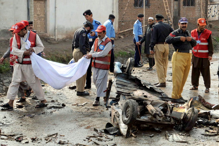 Image: Rescue workers clean up wreckage after a suicide bombing.