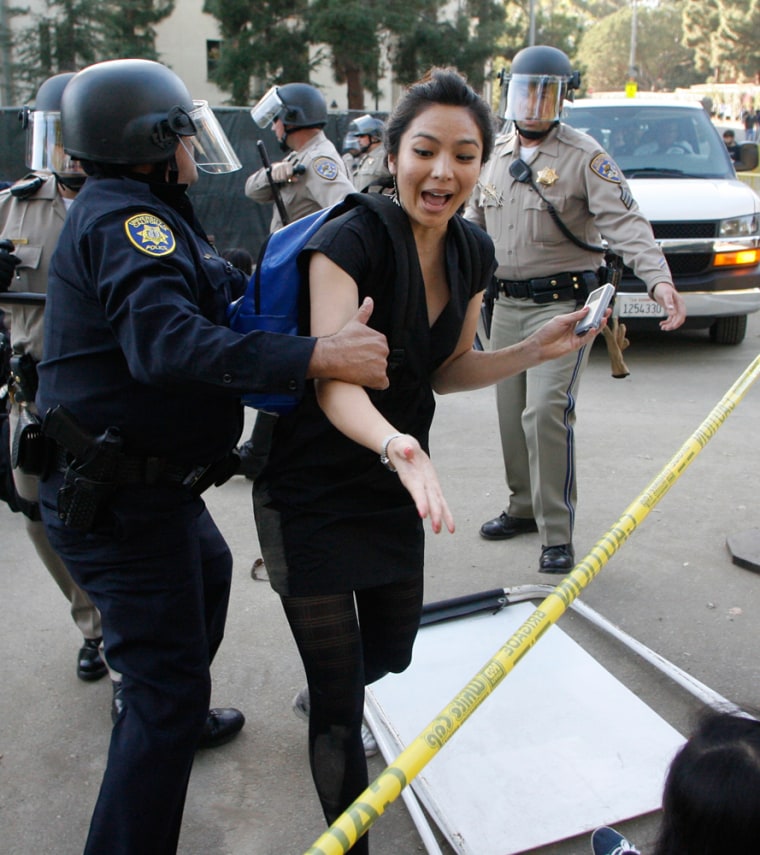 Image: A University of California police officer moves a woman from blocking a road on the UCLA campus