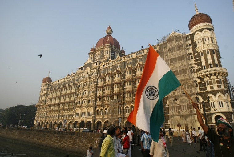 Image: A man walks with the Indian national flag in front of the Taj Mahal hotel in Mumbai