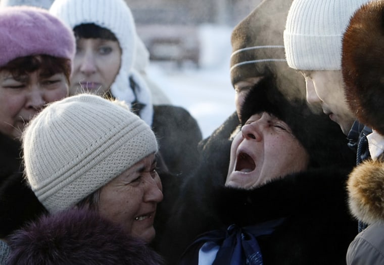 Image: The mother of nightclub fire victim is comforted by relatives during a burial ceremony at a cemetery outside Perm
