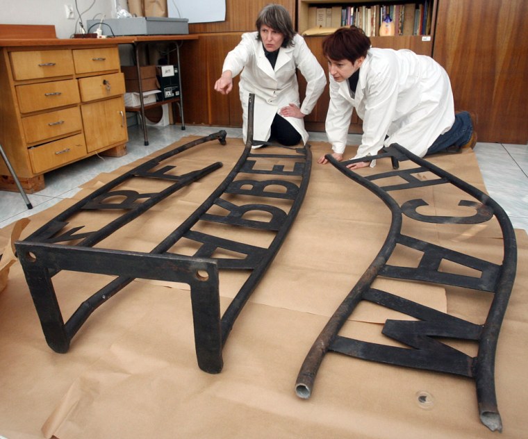 Image: Experts inspect the Auschwitz 'Arbeit macht frei' sign that had been stolen