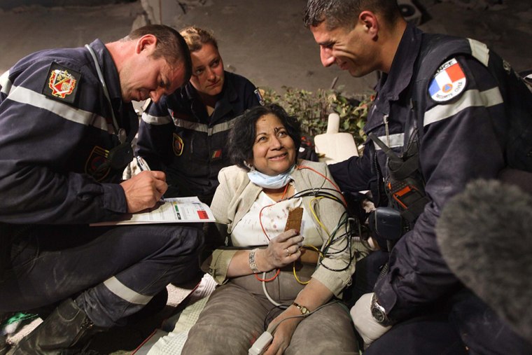 Image: Sarlah Chand ,65, smiles as search and rescue workers tend to her