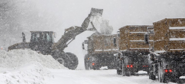 Image: front end loader picks up snow and fills up dump trucks