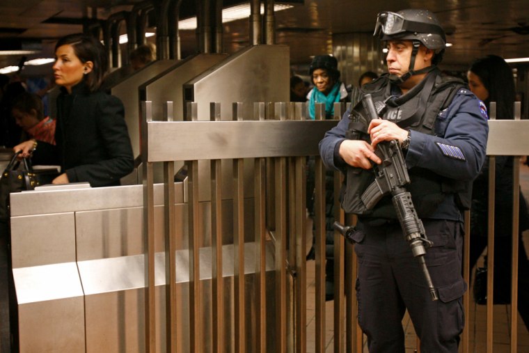 Image: A counterterrorism officer stationed at Grand Central Station in New York keeps his eye on commuters at subway turnstiles