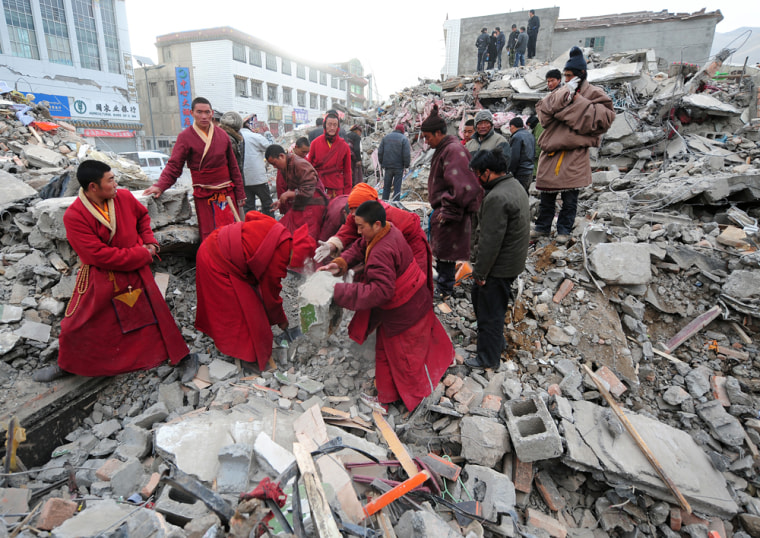 Image: Tibetan Buddhist monks clear debris while searching for survivors amid a collapsed apartment block in Jiegu
