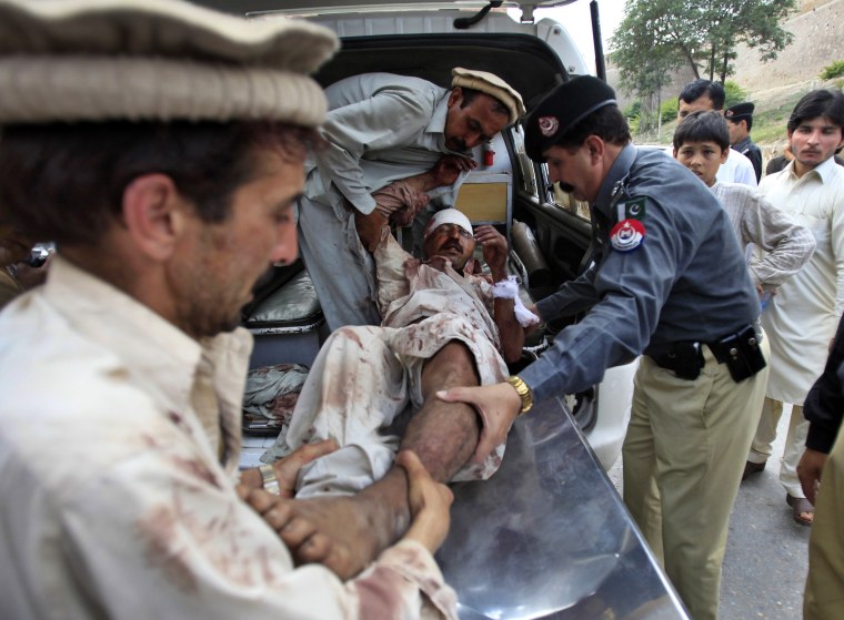 Image: Relatives and a policeman assist a man who was injured in a suicide attack in a village of Kacha Pakha near Kohat