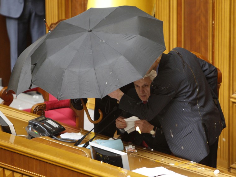 Image: Speaker Lytvyn takes shelter under the umbrella as eggs rain down on him during a session in the Ukrainian parliament in Kiev