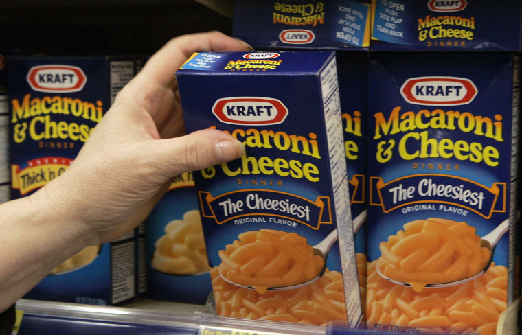 Image: A woman grabs a box of Kraft Macaroni & Cheese from a shelf at a store in Willowbrook