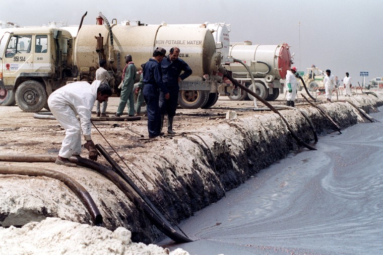 Image: Clean-up workers pump oil from a man-made reservoir.