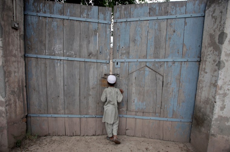Image: A boy looks through the gate of the ancestral home of Shahzad in  Pakistan