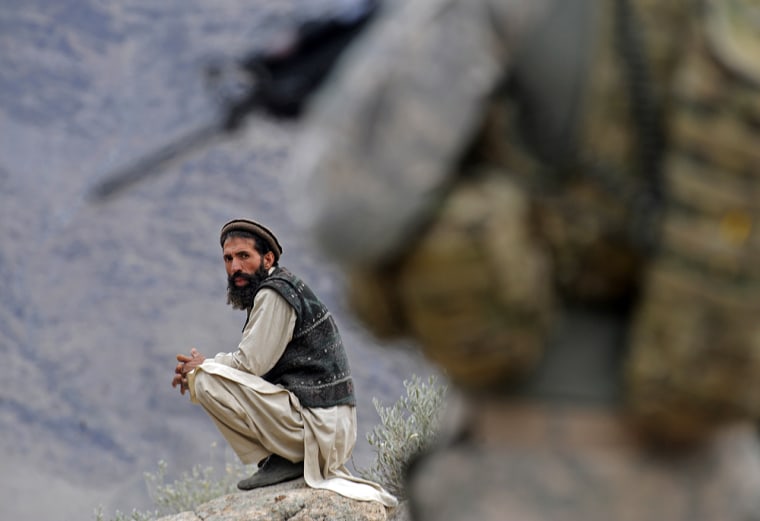 Image: An afghan man looks on as a U.S. soldier patrols
