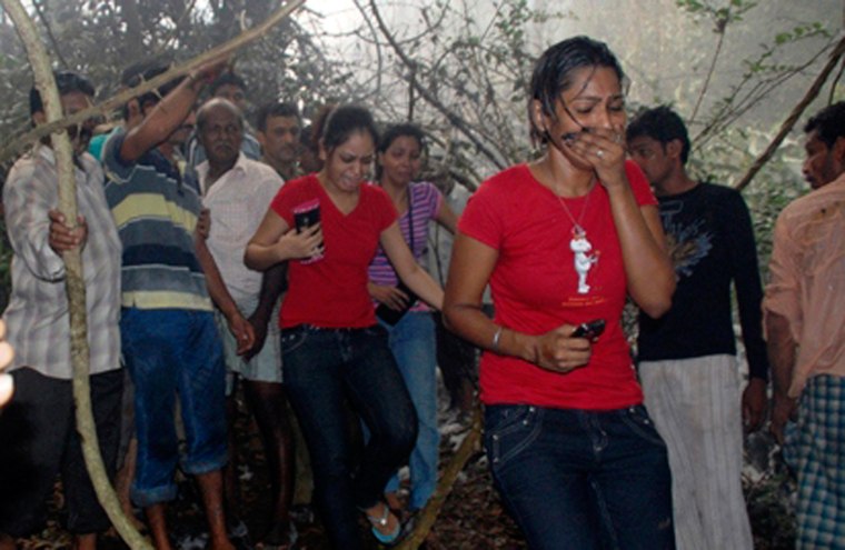 Image: Local residents react after seeing the site of a plane crash in Mangalore
