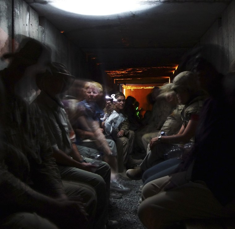 Image: ISAF civilian and military personnel sit in a shelter during a ground and rocket attack by militants at Kandahar Air Field