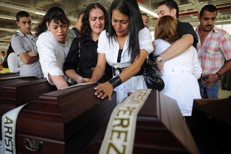 Image: Relatives mourn next to the coffin with the remains of their relative in Medellin