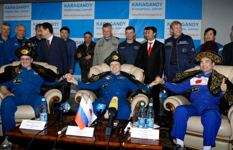Image: Creamer, Kotov and Noguchi sit in Kazakh national costumes at a news conference in Karaganda airport
