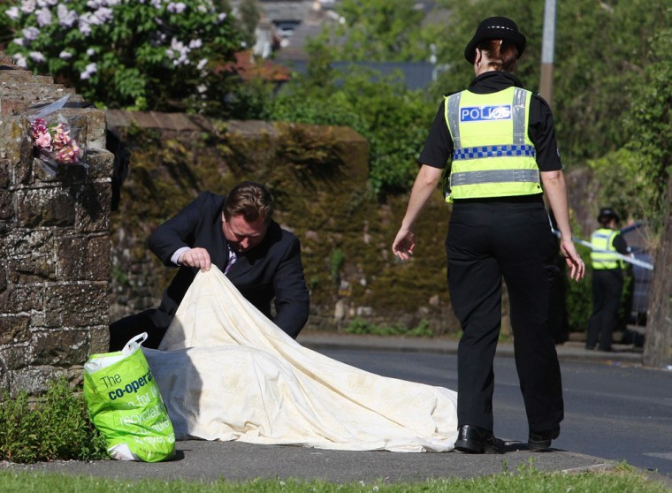 Image: Police look under a sheet covering a body