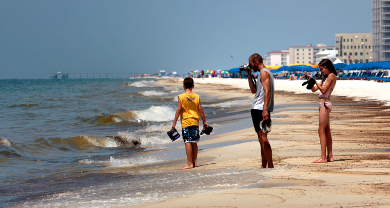 Image: Dale Scheidemantle, center, and his children Josiah, left, and Faith walk near the oily surf in Orange Beach, Ala.