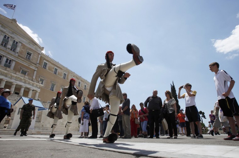 Image: Tourists watch a performance of the Changing of the Guard Ceremony in front of the Greek Parliament Building in Athens