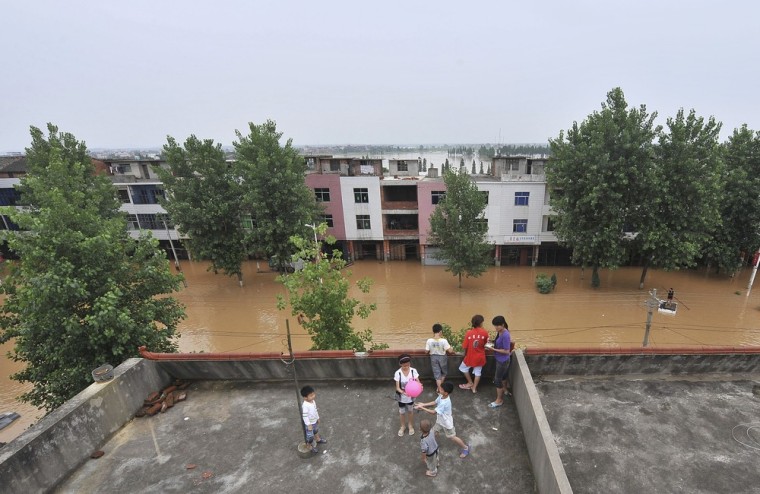 Image: Residents stay on the roof of their homes in the flooded area in Fuzhou