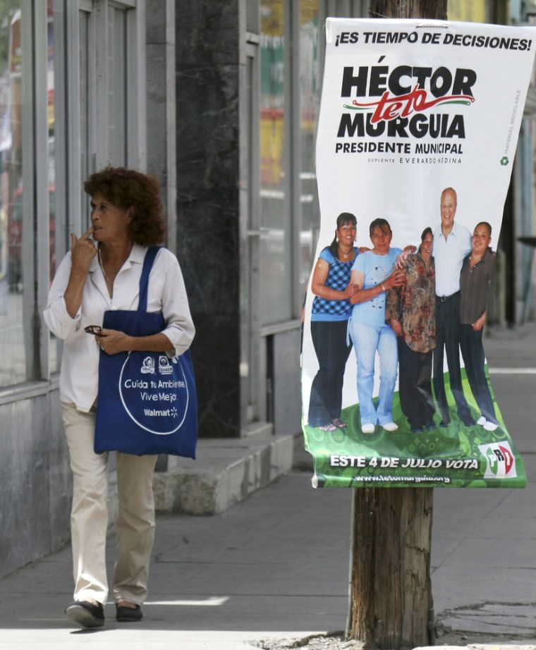 Image: A woman walks next to a poster of a local candidate in Ciudad Jaurez