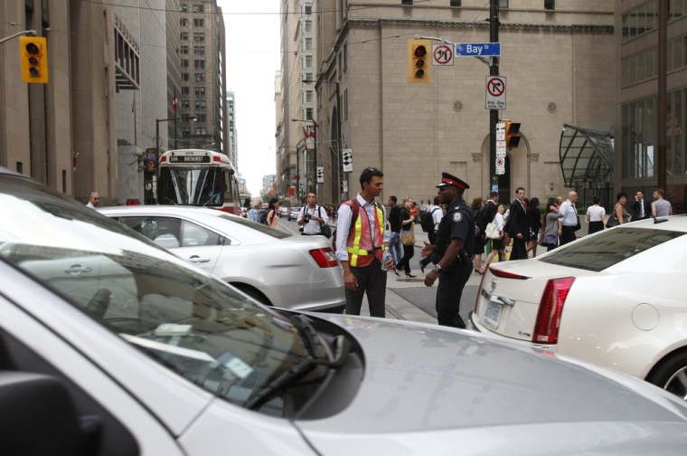 Image: A pedestrian speaks to a Toronto police officer while directing traffic during a power outage in Toronto