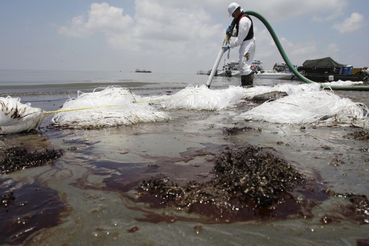 Image: A worker uses a suction hose to remove oil washed ashore from the Deepwater Horizon spill in Belle Terre, La..