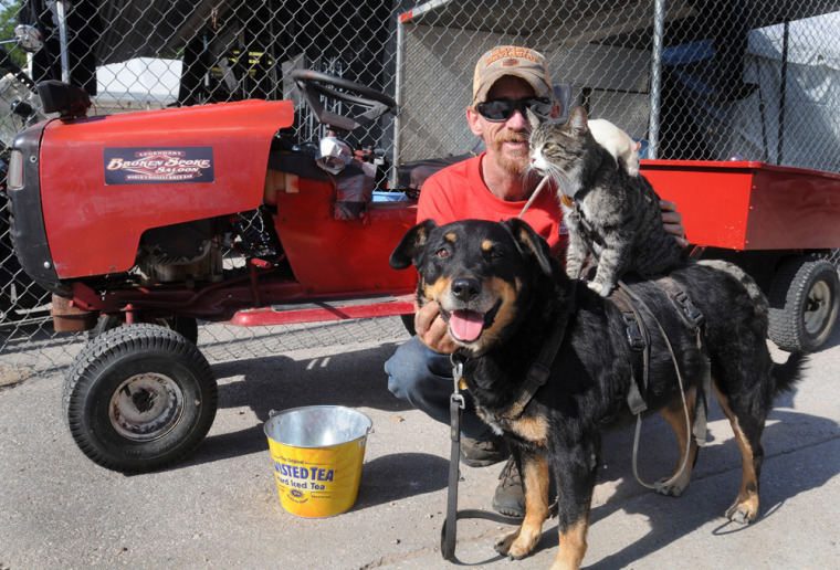 Image: Greg Pike, 50, of Bisbee, Ariz., poses with Booger the dog, Kitty the cat, and Mousey the rat, in front his souped-up riding lawnmower