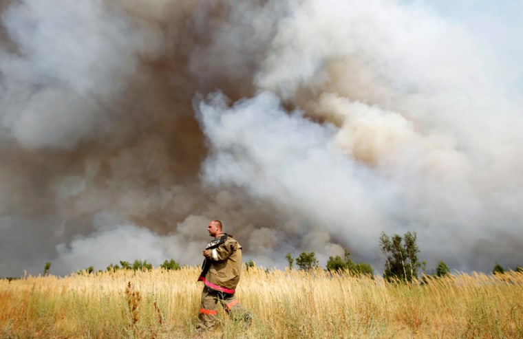 Image: A firefighter walks in a field while smoke from a wildfire cloud the air outside the settlement of Kustarevka in Ryazan region