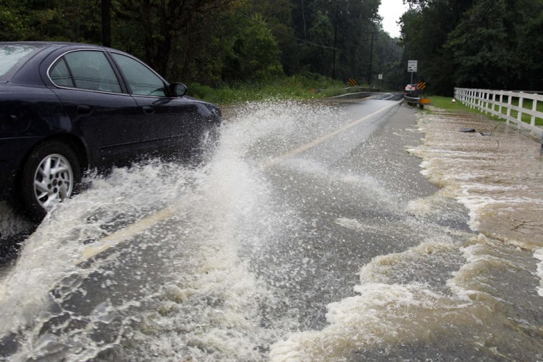 Image: A car drives through water covered Hunter Mill Road in Fairfax, Va