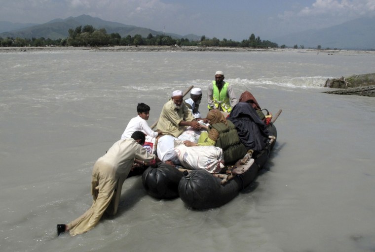 Image: A man pushes a makeshift boat transporting residents from the Sawat river to Fizaghat in Pakistan's Swat Valley