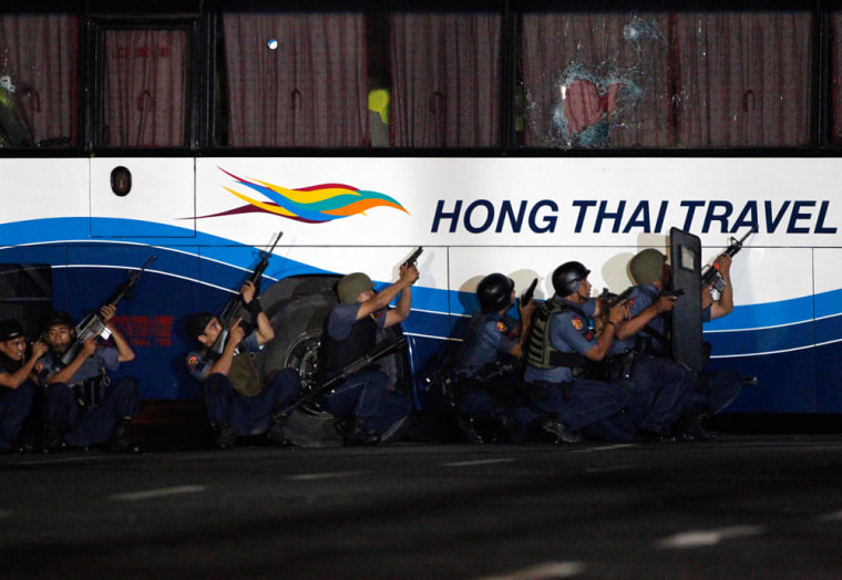 Image: Police commandos take cover as the hostage taker fires at them while they assault a bus with tourists being held hostage at Quirino Grandstand in Manila