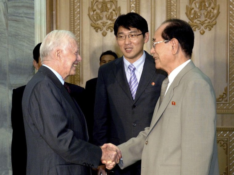Image: Former U.S. President Carter shakes hands with Kim, president of the Presidium of the Supreme People's Assembly of North Korea, during their meeting at the Mansudae Assembly Hall in Pyongyang