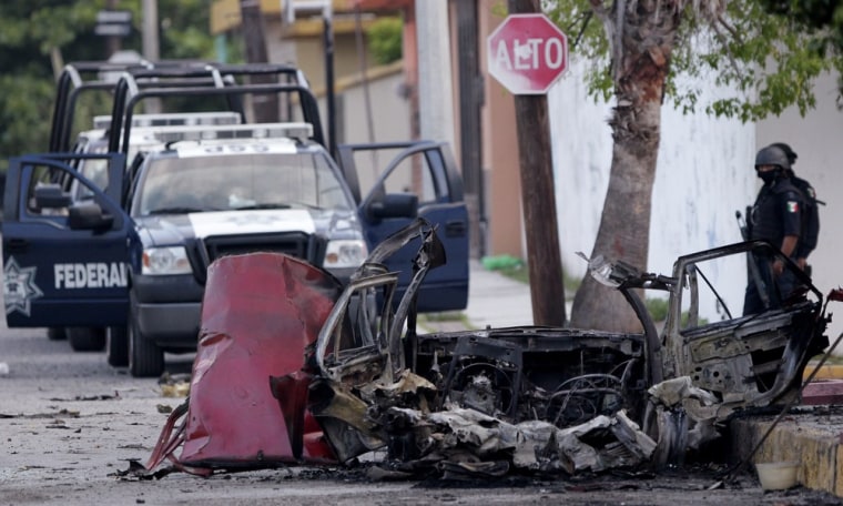 Image: Soldiers stand guard next to remains of a parked vehicle outside a studio of top broadcaster Televisa in Ciudad Victoria