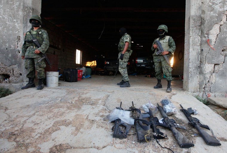 Image: Soldiers stand next to weapons seized at a warehouse after a gunfight with drug gang members at a ranch near Monterrey