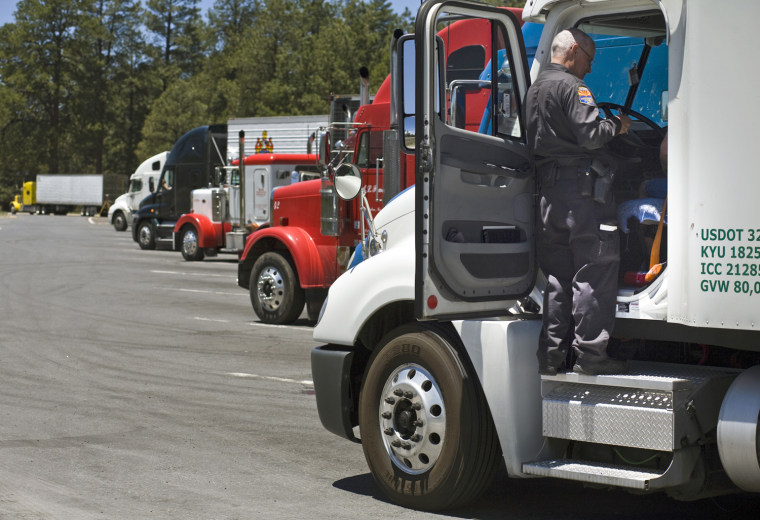 An officer with the Arizona Department of Public Safety talks to a trucker during a road check outside of Flagstaff, Ariz., on June 10. Equipment is checked and truckers are asked to produce a medical certificate that says they are fit to drive. (Photo by AJ Maclean/News21)