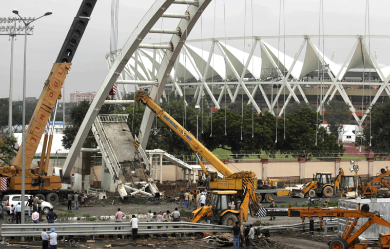 Image: A crane lifts debris from a pedestrian bridge that collapsed