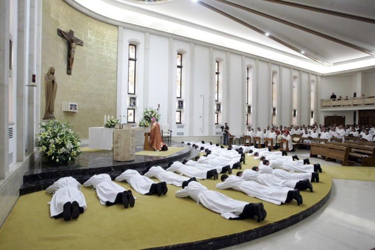 Image: New deacons prostrate  in front of the altar during their ordination mass at the Legionaries of Christ center