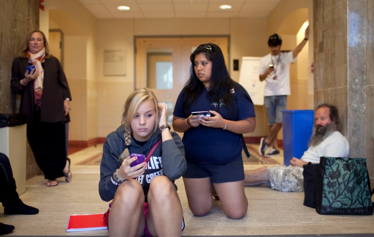 Image: University of Texas students and faculty hold their phones for updated text messages inside Benedict Hall on campus in Austin .
