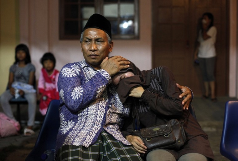 Image: Two colleagues of a train crash victim wait outside a hospital morgue in Pemalang in Indonesia's central Java province
