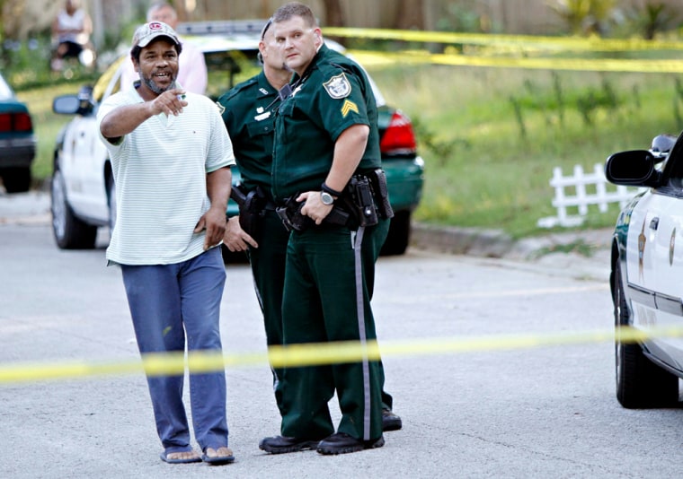 Image: A witness speaks with investigators at one of multiple scenes of a shooting spree involving seven victims in Gainesville.