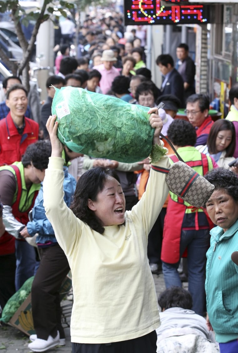 Image: People stand in queues as they wait for their turn to buy cabbages subsidized by Seoul city hall office, at a market in Seoul