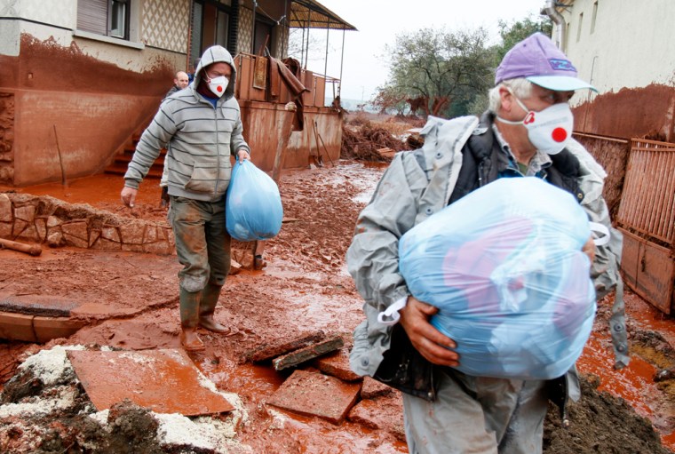 Image: Residents leave their home in the flooded village of Devecser.