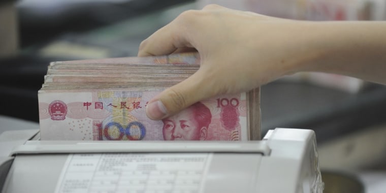 Image: An employee counts yuan banknotes on a currency detector at a branch of Bank of China in Hefei