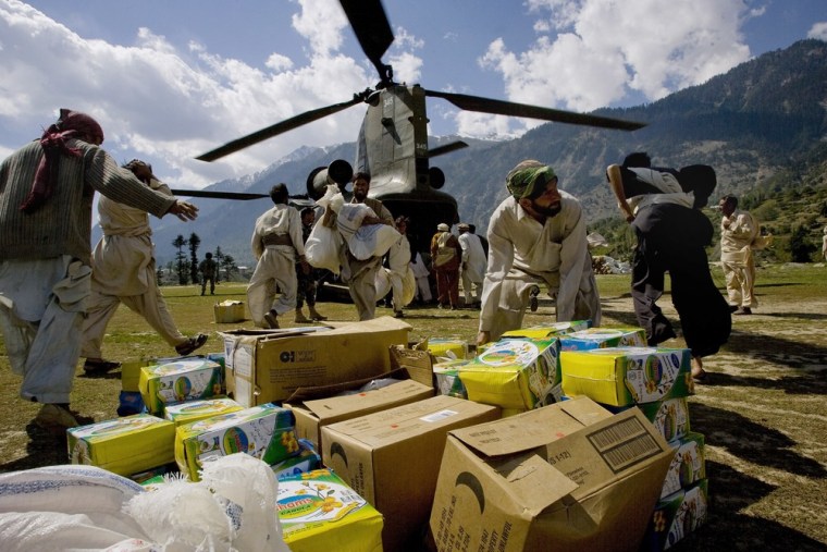 Image: Pakistani volunteers unload relief supplies from a U.S. Chinook helicopter