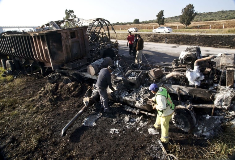 Image: Men examine the charred remains of two vehicles near San Luis Potosi on the outskirts of Queretaro