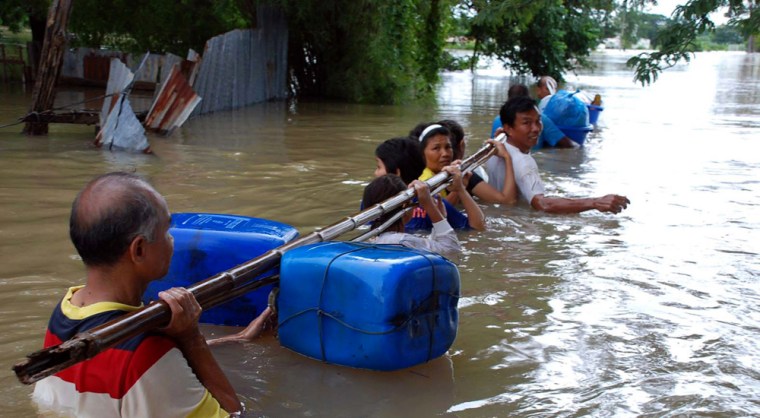 Image: Residents wade through flood water by holding a float-attached pole as they evacuate their homes in Nakhon Ratchasima province, northeastern Thailand.