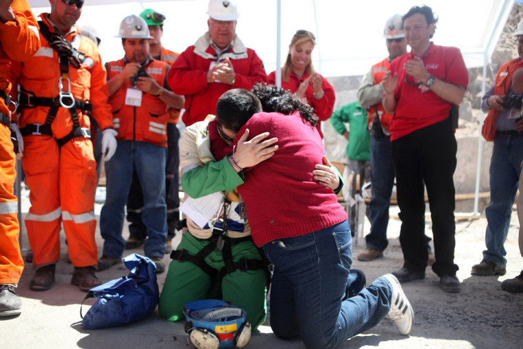 Image: Trapped miner Esteban Rojas hugs his wife as he prays after reaching the surface to become the 18th to be rescued from the San Jose mine in Copiapo