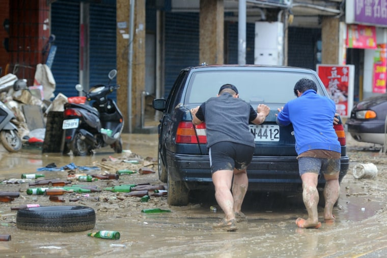 Image: Locals push a car through flood damage i