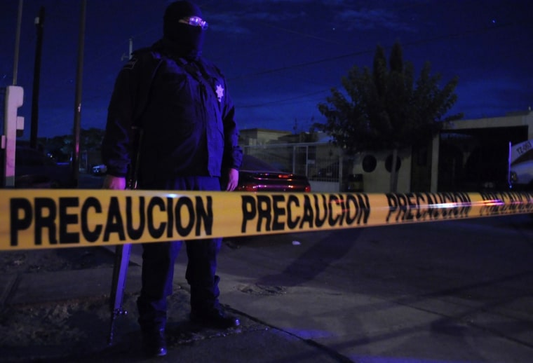 Image: A policeman stands behind a police line near a crime scene in Ciudad Juarez