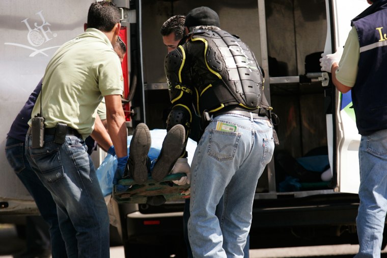 Image: Forensic workers load the body of a dead man into the coroner's vehicle at a crime scene in Guadalajara